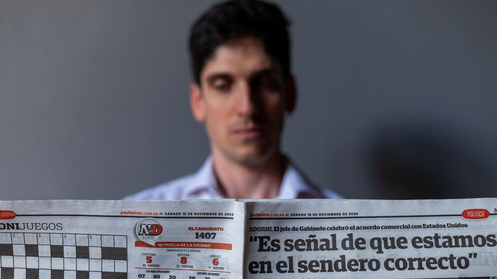 Lector revisando el titular de portada de un periódico en español